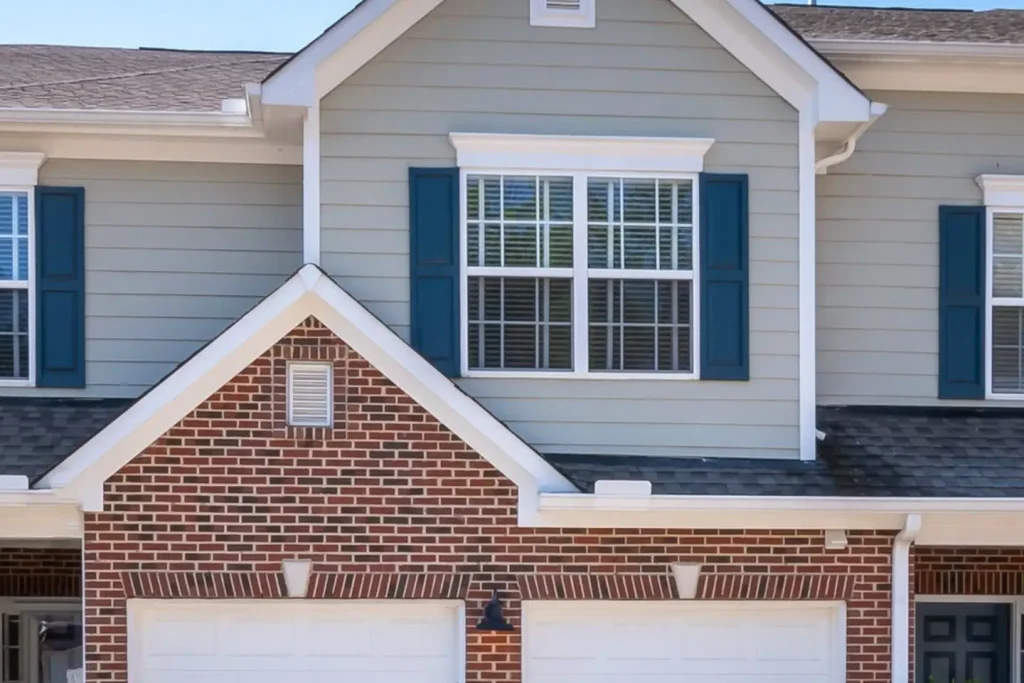 The Oak Cliff Duplex, a two-storey townhome building with grey siding, brick and two garages