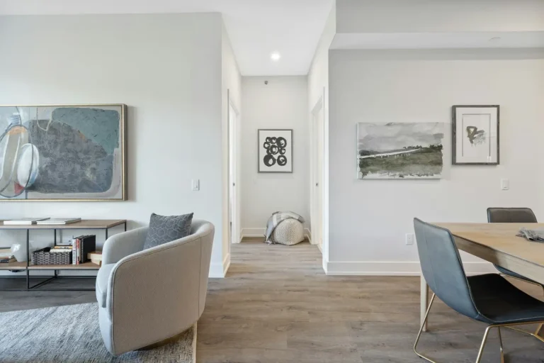 Living and dining area in a bright rental with a grey armchair, framed prints and a wood-look floor